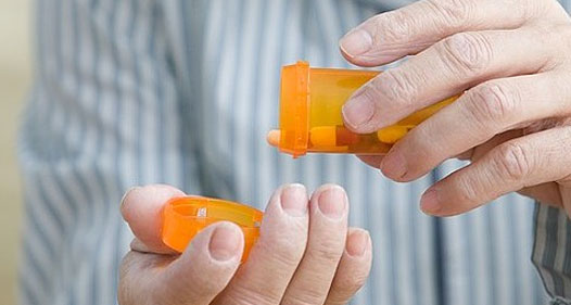 Senior person's hands emptying pills from a bottle.