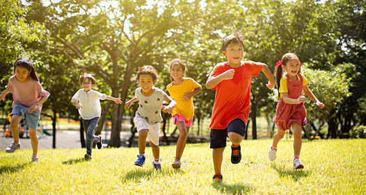 Six young kids running in the grass toward the camera.