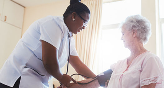 African American medical worker takes an elderly woman's blood pressure.