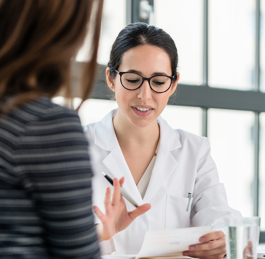 Female doctor in black rim glasses explains prescription to a patient.