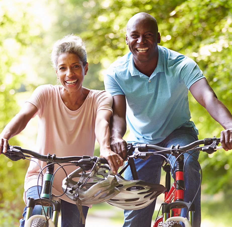 Mature African American couple riding bicycles in the countryside.