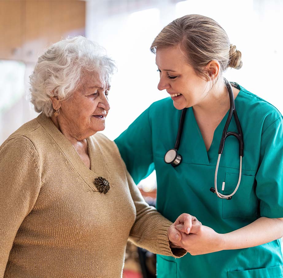 Female health care professional talking to a senior woman during home visit.