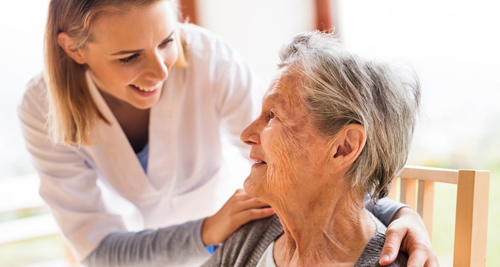 Female health care professional comforts a senior woman.